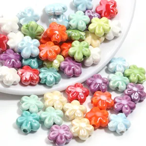 Dettaglio ravvicinato di perle sfuse a forma di fiore a cinque petali in ceramica colorata.