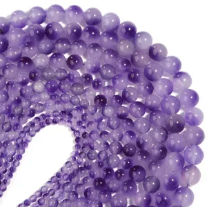 Primo piano di perline tonde in calcedonio viola naturale di varie dimensioni per gioielli.