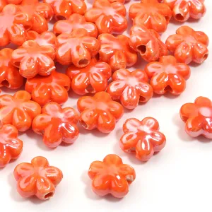 Primo piano dettagliato di perline di ceramica arancione lucido a forma di fiore a cinque petali.