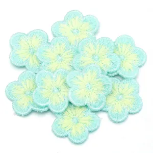Close-up of light blue and yellow embroidered plum blossom patches for DIY crafts and clothing.