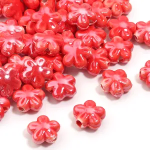 Dettaglio perle di fiori in ceramica rossa, perfette per la creazione di gioielli fai da te e bracciali.