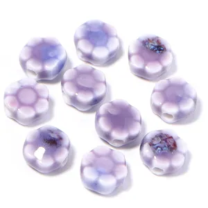 Primo piano di perline di fiori di margherita in ceramica viola, perfette per gioielli fai da te.