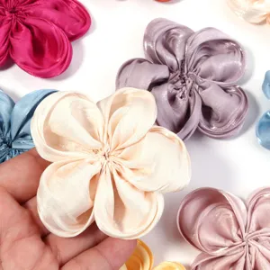 Close-up details of glossy satin fabric five-petal flowers for DIY hair accessories crafting.