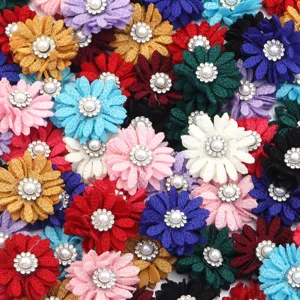 Vista detallada de adornos de flores de tela colorida con perlas y pedrería para manualidades DIY.
