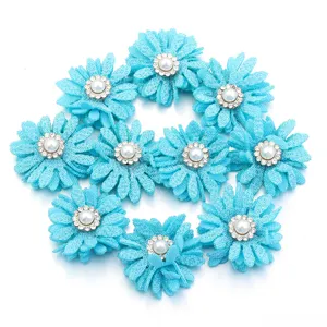 Primer plano de accesorios de flores de margarita de tela azul con perlas y pedrería.