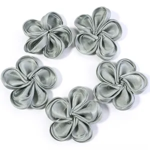 Close-up detail of silver fabric five-petal flower DIY accessories, glossy texture.