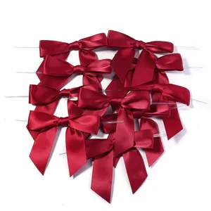 Vue détaillée de nœuds en ruban de satin rouge vin avec liens métalliques pour emballage de cadeaux.