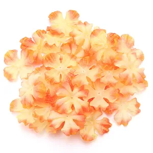 Close-up detail of artificial fabric four-petal flower patches in orange gradient DIY craft.