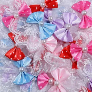 Gros plan de nœuds en satin à pois colorés avec des perles et de la dentelle blanche.