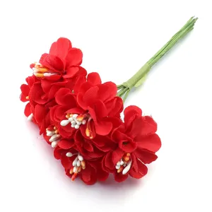 Primer plano de un ramo de flores de camelia de tela artificial roja con tallos verdes.