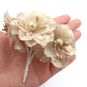 Detalle de ramo de flores de tela artificial dorada, centro brillante decorativo