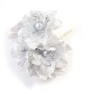 Detalle de flor artificial de tela con purpurina plateada, ideal para manualidades y decoración.