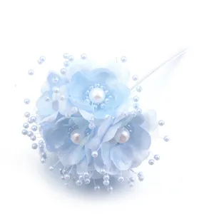 Detalle de flor de camelia de tela artificial azul con perlas para decoración de bricolaje.