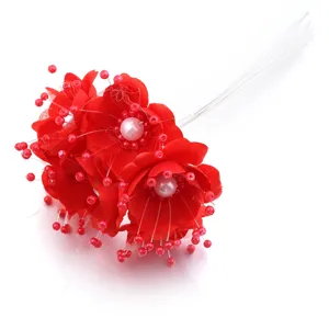 Primer plano detallado de flores de camelia de tela roja con estambres de perlas para manualidades.