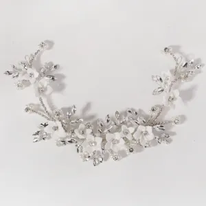 Handgemaakte bruids haarwijnstok detail met witte keramische bloemen, strass en parels.