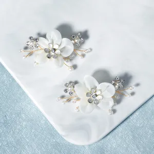 Detail view of handmade white flower shoe clips with pearls and rhinestones for bridal shoes.