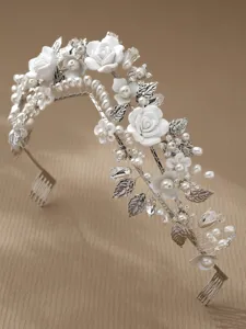 Detail shot of bridal hair accessory featuring white clay roses, pearls, and silver leaves.
