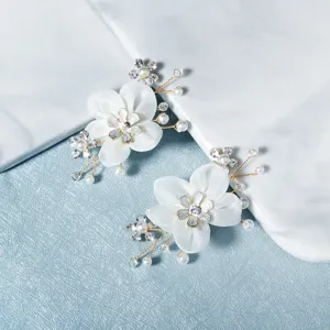 Handcrafted white floral shoe clips with pearls and rhinestones, perfect bridal high heel accessories.