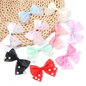 Close-up details of multi-color bow hair clips featuring delicate mesh and pearl decorations.