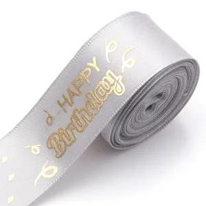 Detailed shot of silver satin ribbon with gold foil happy birthday print for gift wrapping.