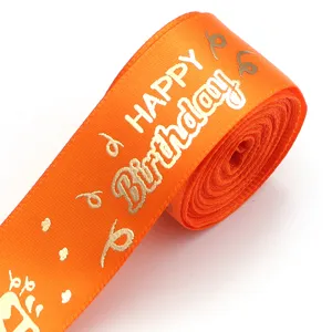 Close-up detail of orange ribbon with gold hot stamping Happy Birthday print for gift wrap.