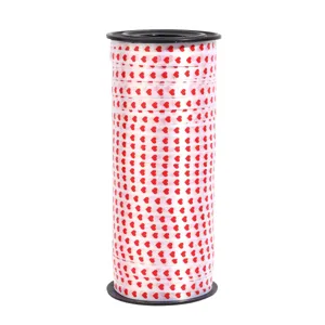 Close-up detail of white ribbon roll with red heart patterns for gift wrapping and party.