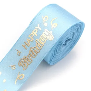 Close-up detail shot of light blue satin ribbon featuring gold foil Happy Birthday print.