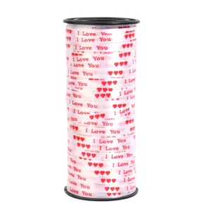 Close-up detail of white ribbon roll with red hearts and I Love You print for gift wrapping.