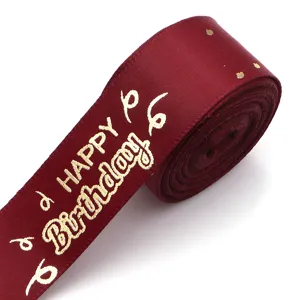 Close-up of burgundy satin ribbon with gold foil happy birthday print for gift wrapping.