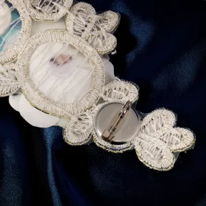 Primer plano del reverso de un broche de flor de encaje artesanal con seguro cierre.