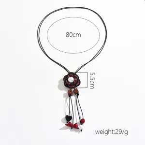 Long sweater chain necklace featuring a delicate woven flower pendant with pearl and charms.