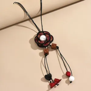Exquisite fabric camellia sweater chain pendant detail, featuring pearl and delicate charms.