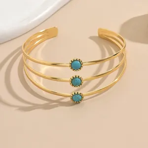 Bracciale cuff aperto dorato multistrato alla moda con pietre turchesi sintetiche.