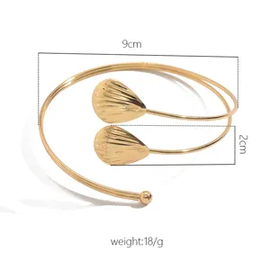 Primo piano di un bracciale da braccio dorato minimalista con dettagli di conchiglie.