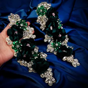 Detalle de aplicación de pedrería de flores de tela verde oscura hecha a mano para vestido de traje.