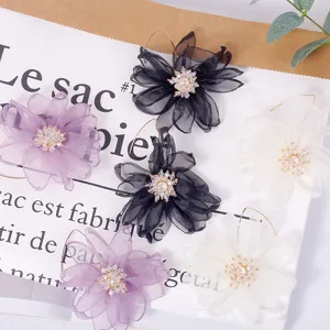 Primo piano dettagliato di orecchini a fiore in tessuto a rete coreano con strass brillanti.