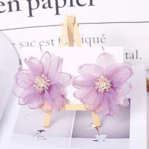 Primo piano dettagliato di orecchini a fiore in tessuto mesh viola con strass luminosi.