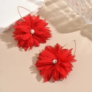 Exaggerated red fabric flower earrings with gold hooks and pearl rhinestone center detail.