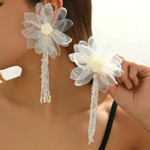 Nahaufnahme von weißen Stoffblumen Ohrringen mit zarten Perlenquasten und feinen Spitzenblüten.