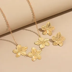 Goldfarbene Metallblumen Halskette und Ohrringe Detailaufnahme mit feiner Textur.