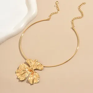 Close-up detail of the irregular gold flower pendant and metallic choker chain design.
