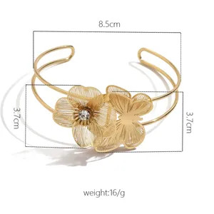 Bracciale rigido aperto dorato con motivi di fiori e farfalle in rete metallica con strass.