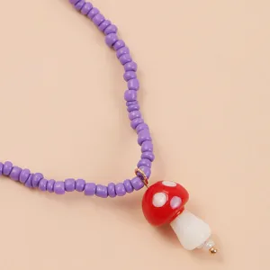 Close-up detail view of the purple beaded necklace featuring a cute red mushroom pendant design.