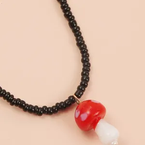 Close-up detail of a sweet beaded black necklace with a cute red mushroom pendant for women.