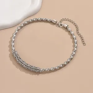 Primer plano detallado de un collar choker de metal plateado trenzado con pedrería.