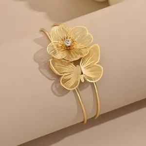 Bracciale da braccio aperto dorato con fiore filigranato, farfalla e strass lucido.