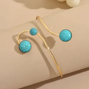 Manchette de bras ouverte dorée avec perles turquoise, bijou de corps géométrique élégant.
