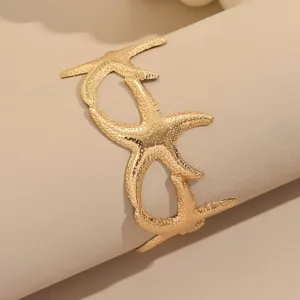 Primer plano detallado del elegante brazalete de estrella de mar dorada, diseño metal.