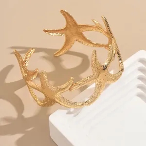 Detalle en primer plano de la pulsera brazalete con diseño de estrella de mar dorada.