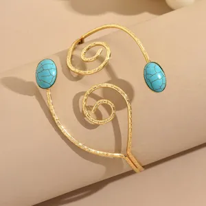 Dettaglio in primo piano di un elegante bracciale da braccio a spirale geometrico.